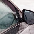 A car's side view mirror is fogged up. The reflection of the car is blurry and the mirror is covered in frost